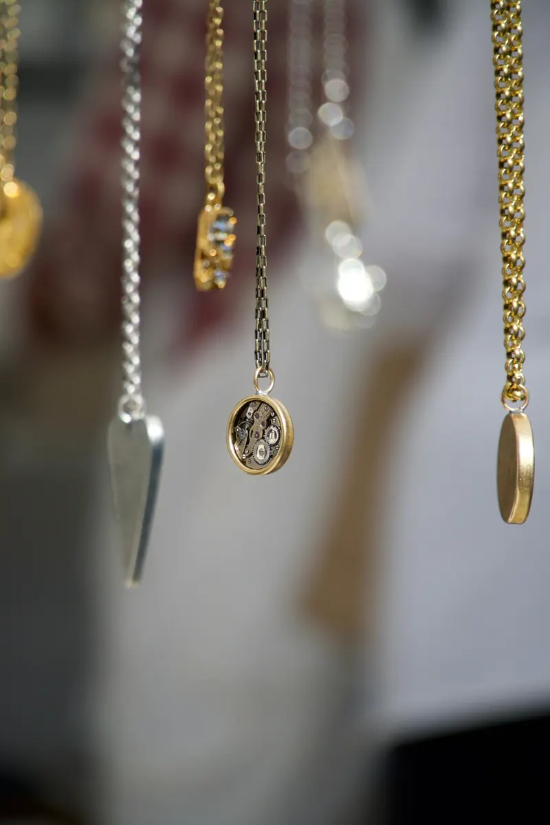 Long delicate gold chain drop earrings hanging against a soft background, a chain style similar to dangling cross earrings for men