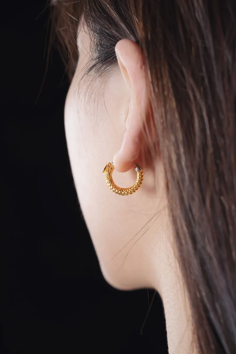 Profile of an ear wearing a textured gold huggie hoop against a black background, similar in spirit to Jason Aldean earrings