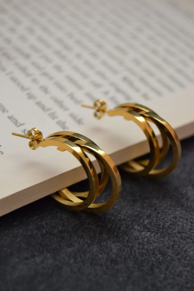 Chunky gold double hoop earrings resting on an open book